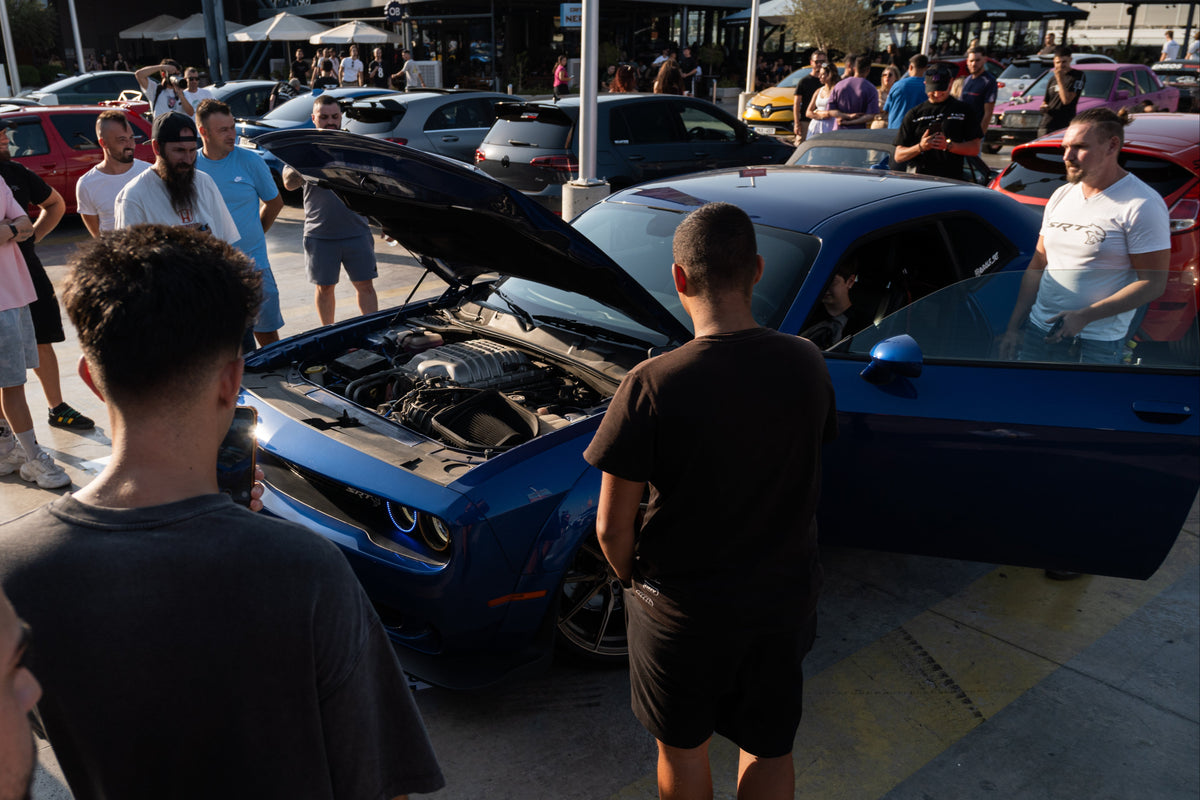 Blue car with open hood at a car show with people around