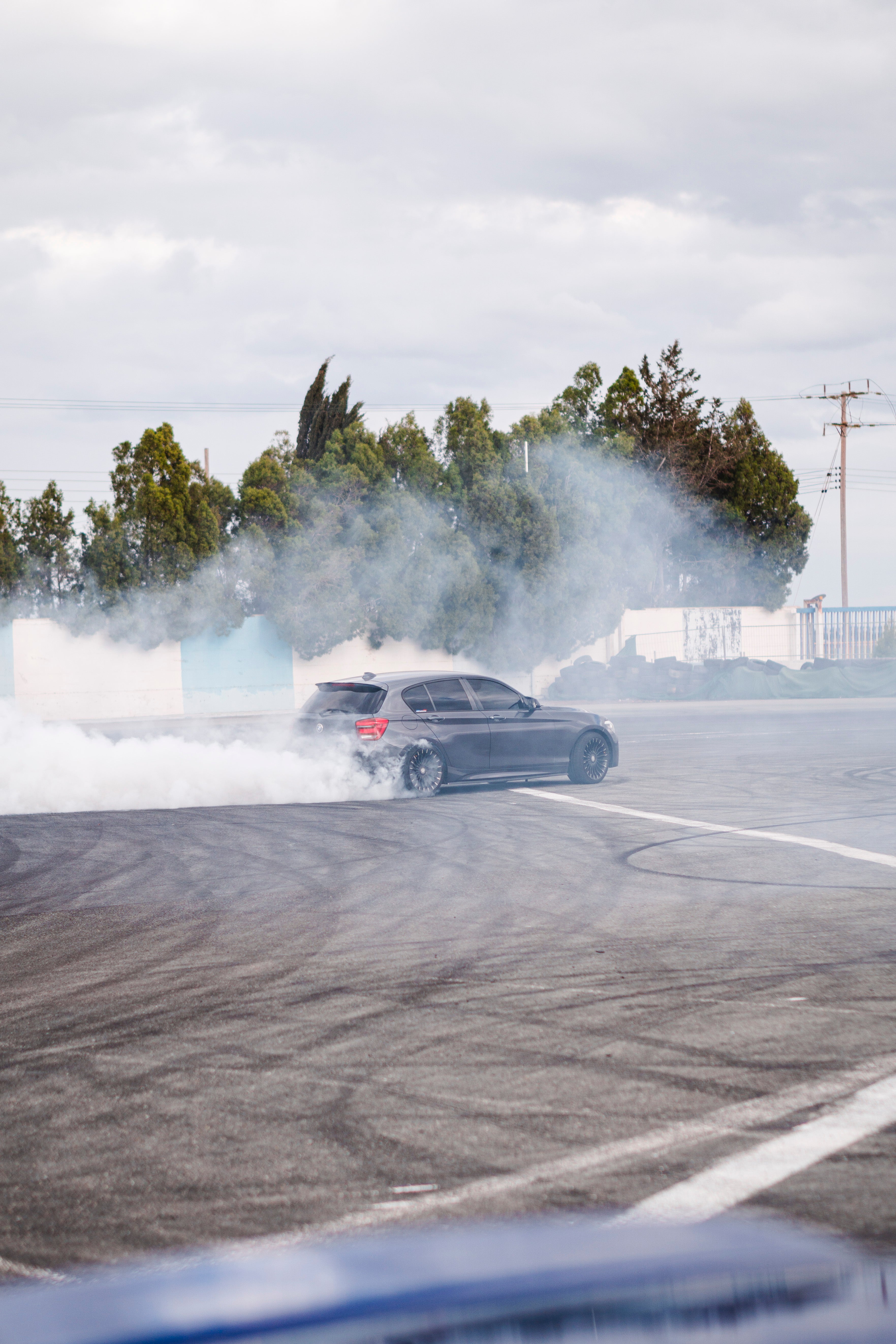 Car performing a drift on a road with smoke trailing behind