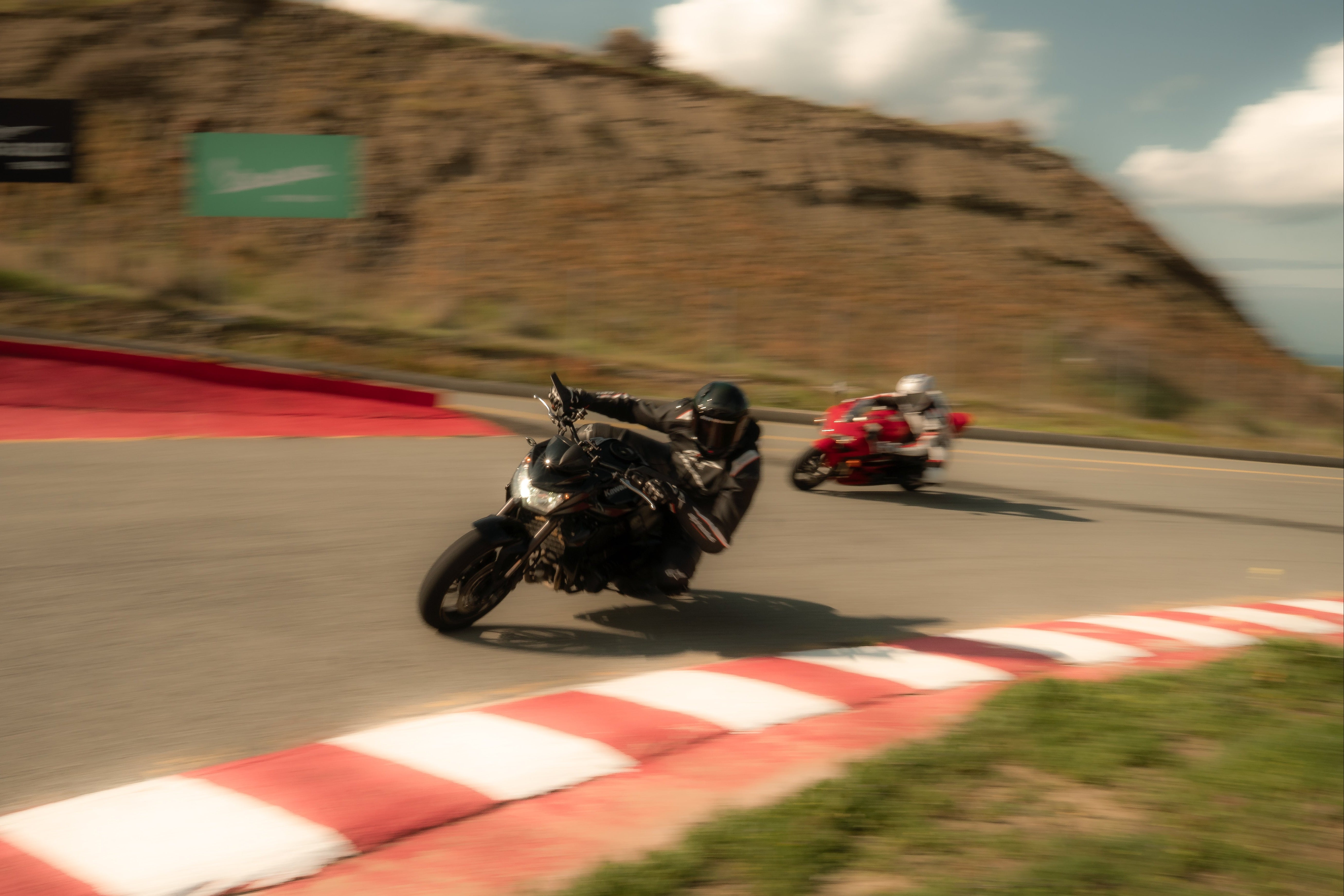 Two motorcycles racing on a track with a mountainous background